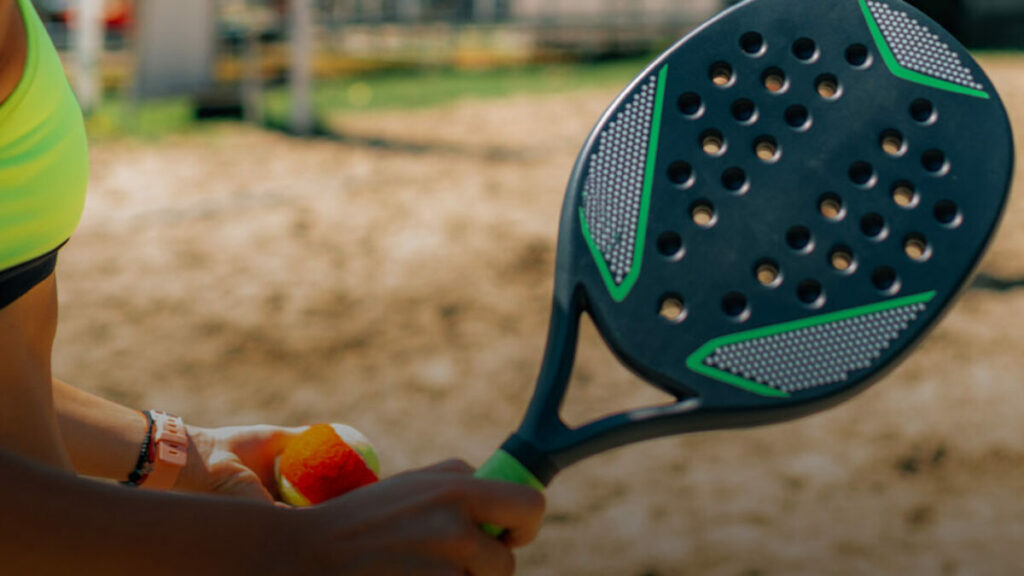 Jogador de beach tennis segurando raquete azul