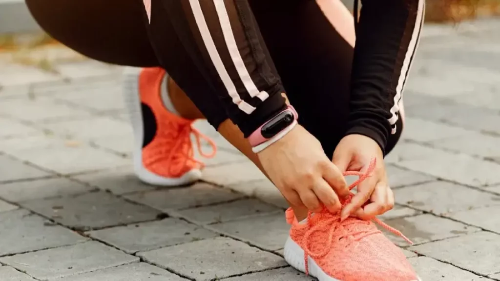 Mulher abaixada amarrando seu tênis para crossfit feminino