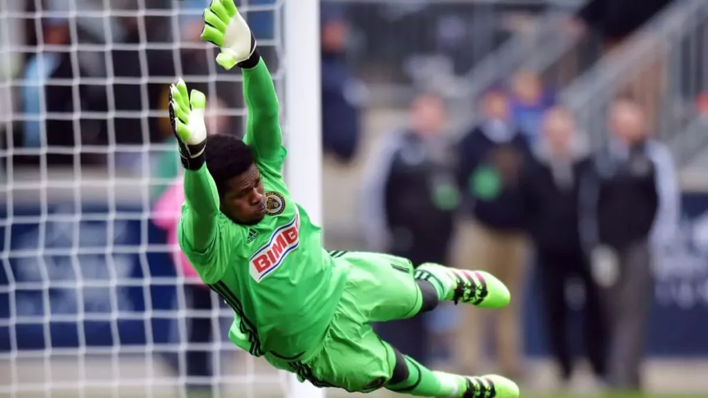 Goleiro fazendo defesa com enfoque as suas luvas