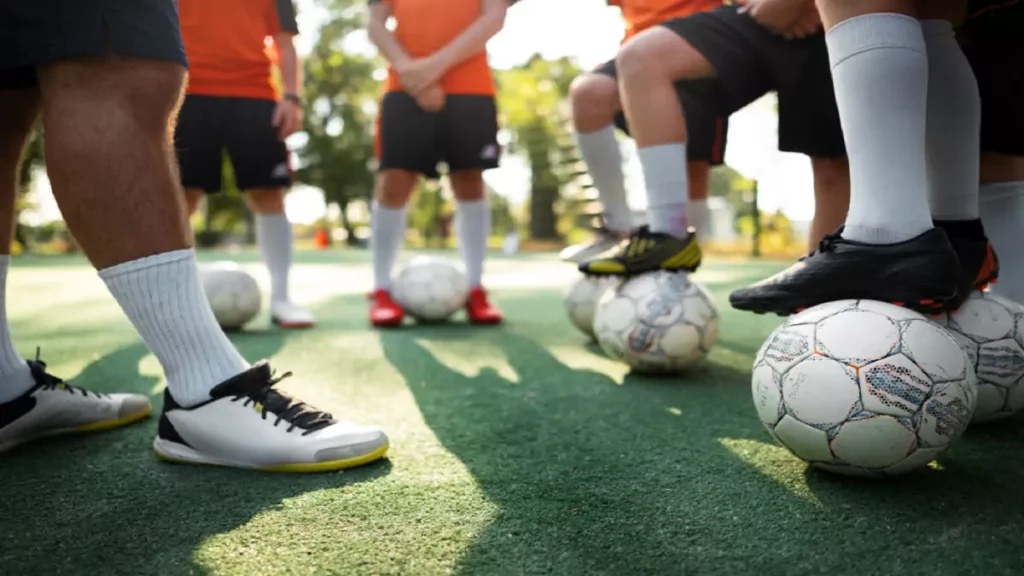 Foco nas pernas de jogadores que estão calçando chuteiras de society